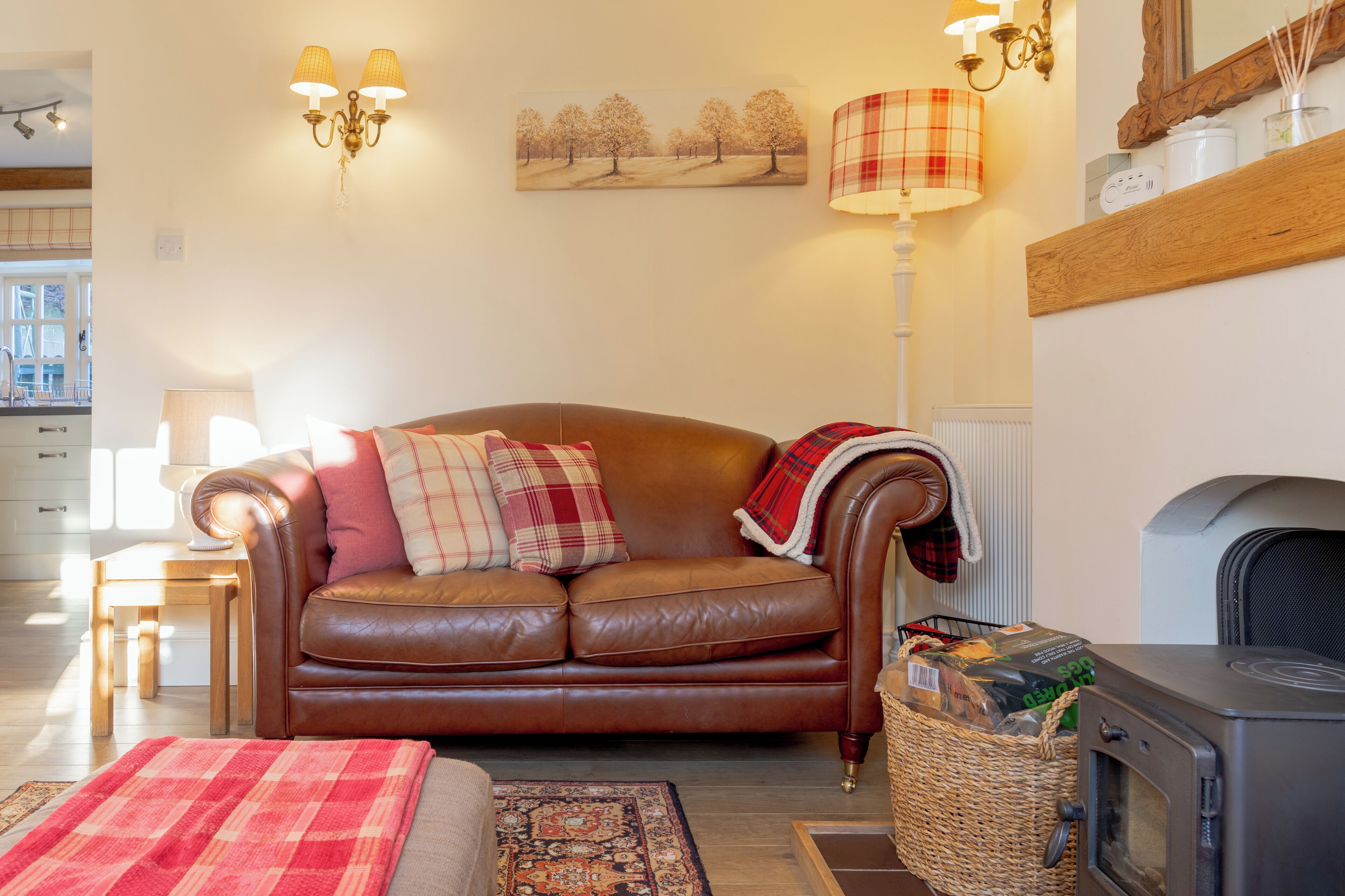 A cozy living room with a brown leather sofa, a fireplace, and a dining area in the background.