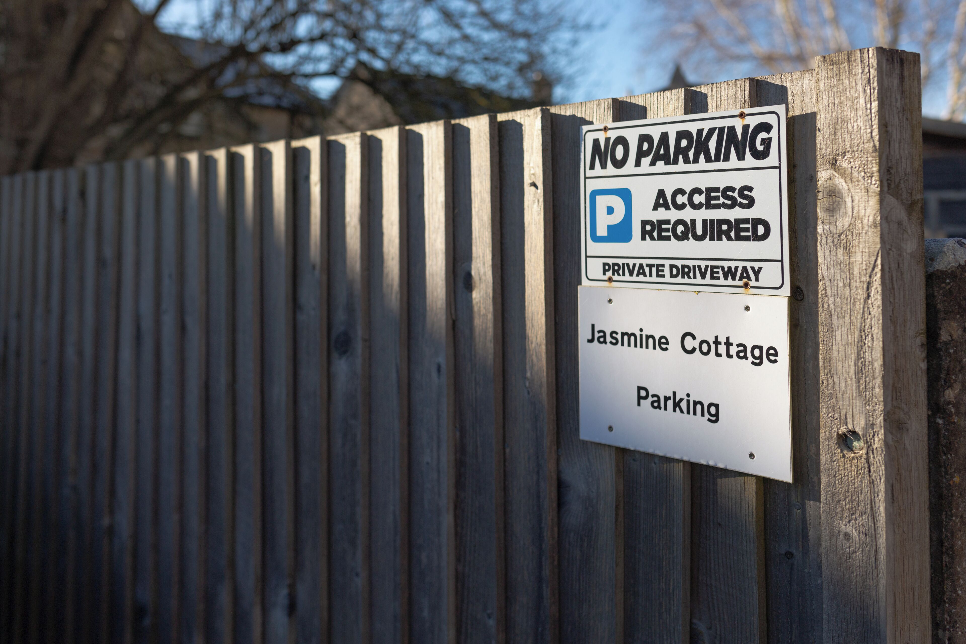 A sign on a wooden fence indicating 'No Parking' and 'Access Required' for a private driveway at Jasmine Cottage.