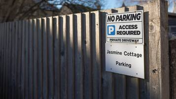 A sign on a wooden fence indicating 'No Parking' and 'Access Required' for a private driveway at Jasmine Cottage.