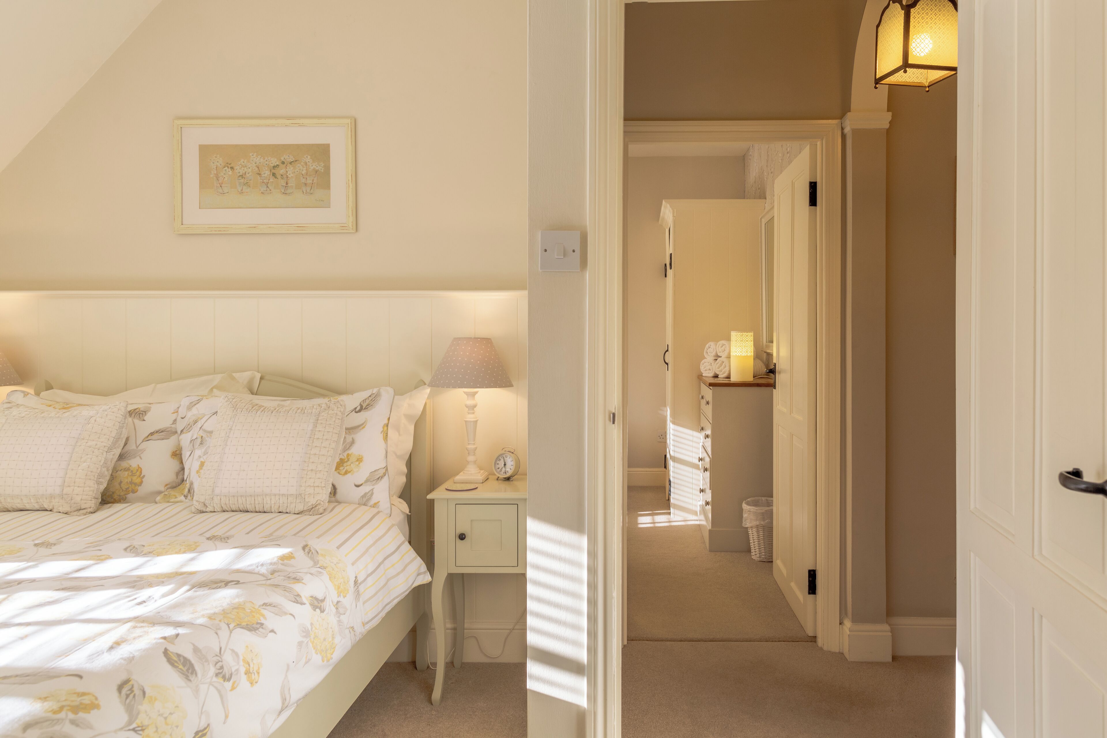 A bedroom with a bed, bedside table, lamp, and a framed picture on the wall.