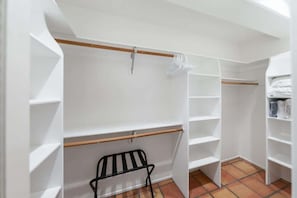 A walk-in closet with open shelving, a wooden rod, and a black metal rack. - Blue Coyote Whole House (Yucca Valley)