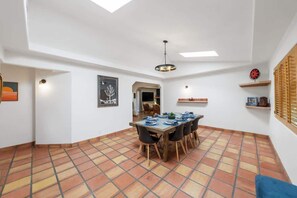 A dining area with a table set for six, a ceiling fan, and a view of the adjacent room.