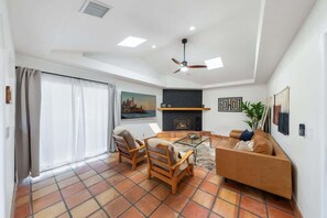 A living room with a fireplace, a sofa, a coffee table, and a ceiling fan.