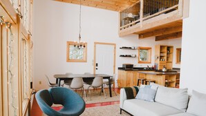 A spacious living area with a high ceiling, a dining table, and a cozy sofa.