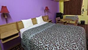 Ein Hotelzimmer mit einem großen Bett, zwei Nachttischen, einem Schreibtisch und einem Stuhl.