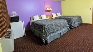 Ein Hotelzimmer mit zwei Betten, einem Schreibtisch, einer Lampe und einer Heizung.