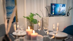 A dining table set with candles, plates, and glasses, with a TV displaying a Netflix interface in the background. - Noble Studio | 1 Min to HBF (Mannheim)