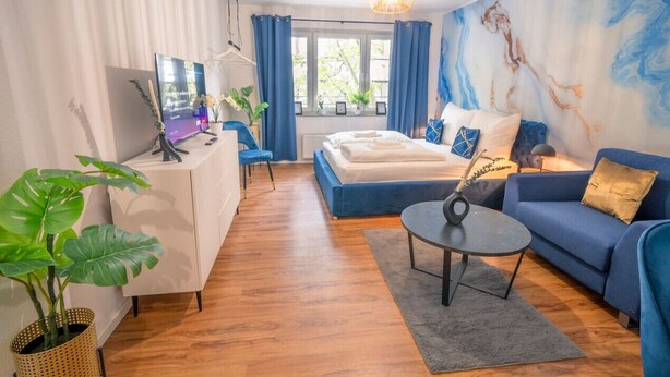 A modern hotel room with a bed, sofa, desk, and a large window. - Noble Studio | 1 Min to HBF (Mannheim)
