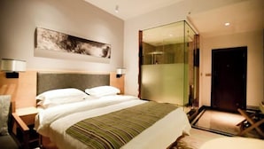 A hotel room with a bed, a large mirror, a painting on the wall, and a door. - Jin tai Hotel (Gejiu)