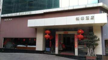 A hotel entrance with a modern facade, a red lantern decoration, and a potted plant.