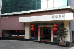 A hotel entrance with a modern facade, a red lantern decoration, and a potted plant. - Jin tai Hotel (Gejiu)