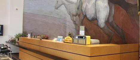 A reception desk with a large abstract painting on the wall behind it.