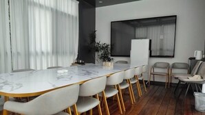 A conference room with a marble table, white chairs, a projector screen, and a potted plant. - Jin tai Hotel (Gejiu)
