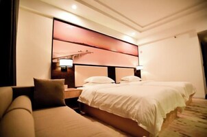 Una habitación de hotel con una cama grande, un sofá y un televisor montado en la pared.