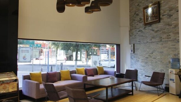 A modern interior with a sofa set, chairs, a coffee table, pendant lights, a large window, and a brick wall. - Jin tai Hotel (Gejiu)