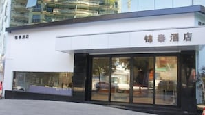 A hotel facade with large glass windows, a white exterior, and a sign in a foreign language. - Jin tai Hotel (Gejiu)