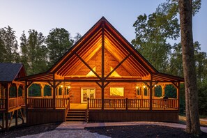A log cabin with a central chimney, a porch with railings, and a staircase leading to the entrance. - Moonlight Ridge Lodge - Hocking Hills (Logan)