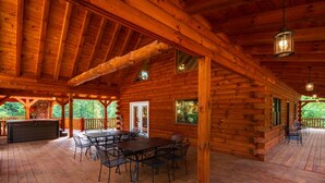A log cabin with a covered deck, a hot tub, and a dining area. - Moonlight Ridge Lodge - Hocking Hills (Logan)