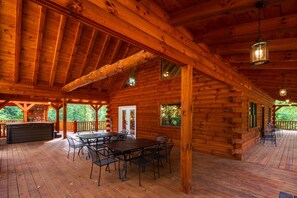 A log cabin with a covered deck, a hot tub, and a dining area. - Moonlight Ridge Lodge - Hocking Hills (Logan)