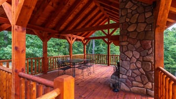 A wooden deck with a stone wall, wooden railings, and a table with chairs.