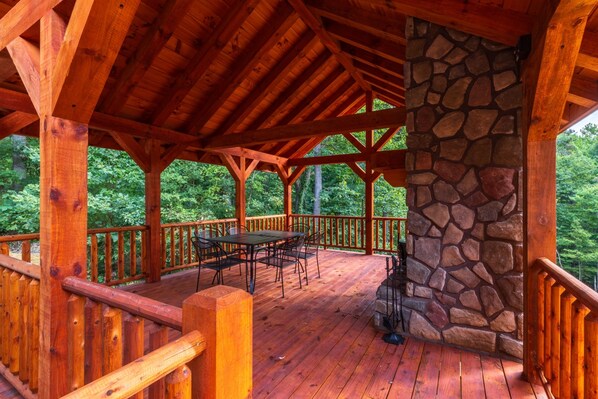 A wooden deck with a stone wall, wooden railings, and a table with chairs.