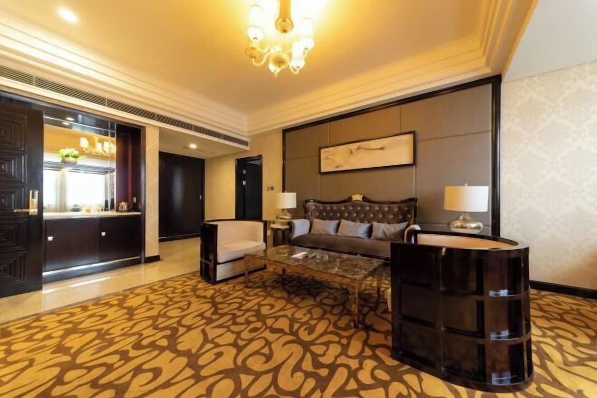 A hotel room with a large bed, a sofa, a coffee table, and a desk.