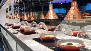 Un buffet avec plusieurs présentoirs de nourriture, des suspensions en cuivre et un aménagement intérieur moderne.