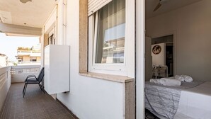 Ein Hotelzimmer mit Bett, Fenster, Stuhl und Blick ins Freie.