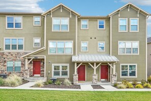 A multi-story residential building with a stone facade, red doors, and a covered entryway.