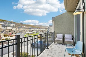 A balcony with a view of a residential area, a parked truck, and outdoor seating.