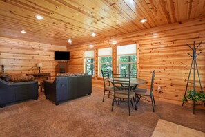 Ein Blockhaus-Interieur mit Essbereich, Sofa und Fernseher.