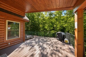 A wooden deck with a covered area, a grill, and a fenced deck.