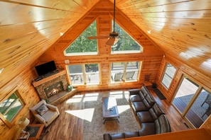 A log cabin with a fireplace, leather sofa, and a television in the living area.