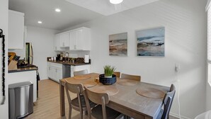 Eine moderne Küche mit weißen Schränken, einem Esstisch mit Holzstühlen und einem Deckenventilator.