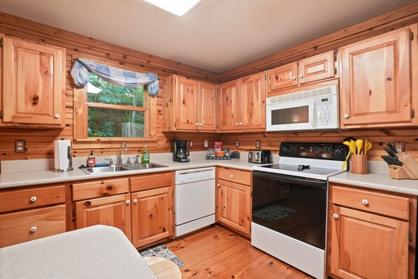 A kitchen with wooden cabinets, a microwave, a stove, and a dishwasher.