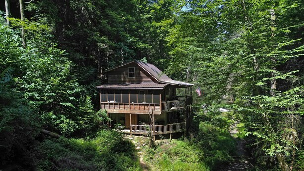 A wooden cabin with a balcony, surrounded by dense forest. - Hidden Falls Retreat | Hocking Hills, Waterfall (Rockbridge)