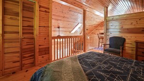 A wooden cabin room with a bed, a chair, and a window. - Hidden Falls Retreat | Hocking Hills, Waterfall (Rockbridge)