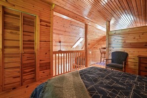 Une pièce de cabane en bois comprenant un lit, une chaise et une fenêtre.