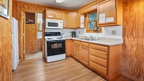 Una cucina con mobili in legno, un forno a microonde, un piano cottura e un lavello.