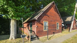 Un piccolo chalet in legno a un piano con un portico, una cassetta delle lettere e un'antenna parabolica.