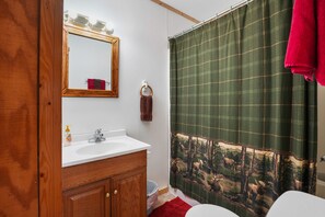 Un baño con tocador de madera, un espejo, un lavabo y una cortina de ducha con estampado de vida silvestre.