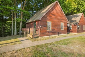 A rustic log cabin with a front porch, a small deck, and satellite dishes.