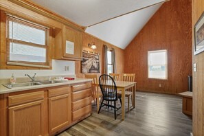 A kitchen with wooden cabinets, a sink, and a dining area with chairs.