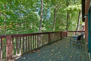 A wooden deck with a table and chairs, surrounded by trees.