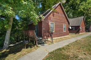A rustic log cabin with a porch and a mailbox.