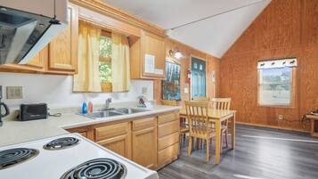 A kitchen with wooden cabinets, a white stove, a sink, and a dining area with a table and chairs.