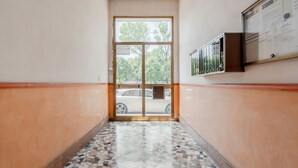 A hallway with a tiled floor, a glass door, and a wall-mounted information board.