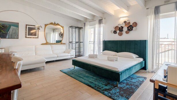 A modern bedroom with a bed, a sofa, a dining table, and a large mirror.