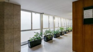 A corridor with large windows, potted plants, and a bulletin board. - GuestHost - Porta Venezia - Modern Studio near Corso Buenos! (Milano)