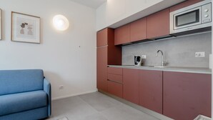 A compact kitchen with a microwave, sink, and red cabinets. - GuestHost - Porta Venezia - Modern Studio near Corso Buenos! (Milano)
